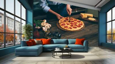 Young woman in kitchen making delicious homemade pizza on rustic kitchen table at home. Italian rural cooking still life. Chef hands preparing homemade food. Healthy foods, cooking concept. Wall mural