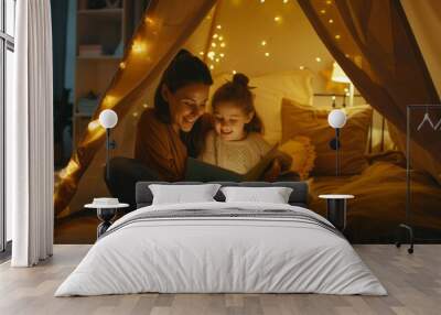 A woman and a child are sitting in a tent reading a book Wall mural