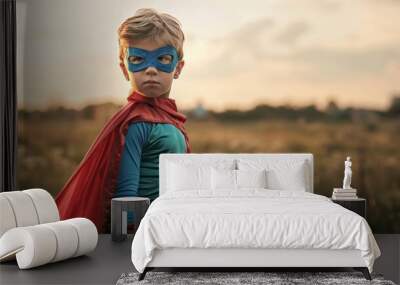 A young boy in a blue superhero costume stands in a field Wall mural