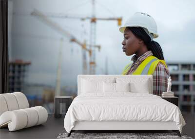 A side view of a black woman in construction using a tablet in a winter scene on the roof on construction site Wall mural