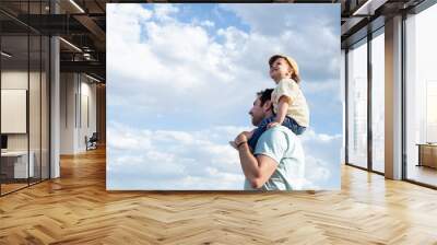 side view of a smile little girl, looking up and sitting on her father's shoulders on a background o Wall mural