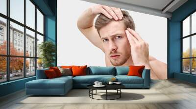 Portrait of young man looking on camera. He hold hands on hair. He is worried. Isolated on white background. Wall mural