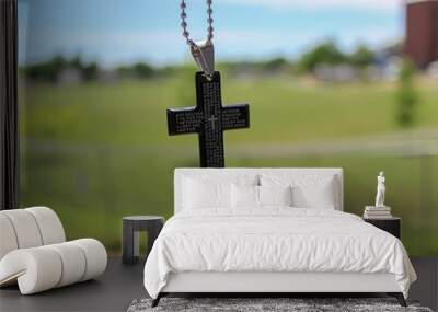 Selective focus shot of a cross against a blurred green background Wall mural