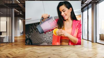 Beautiful fit women preparing shake after doing training. Wall mural