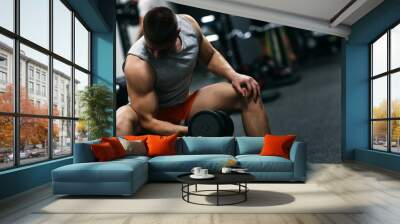 Fit man in sportswear focused on exercise for biceps in the gym Wall mural