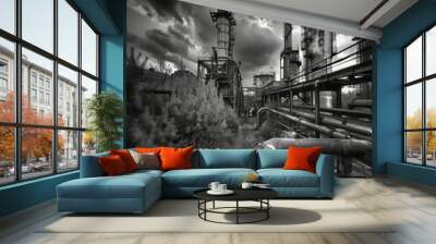 black and white photograph, an expansive view of an abandoned industrial complex, with towering, rust-covered steel structures, overgrown vegetation cloudy sky, high contrast Wall mural