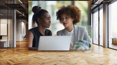 In a contemporary office, two professional women work together, exchanging thoughts and ideas on a project. Women's Equality Day, a manager looks after a young employee. Girl power, women's teamwork Wall mural