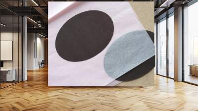 two machine-cut ovals one on and another under pink tissue paper on plain brown paper background Wall mural