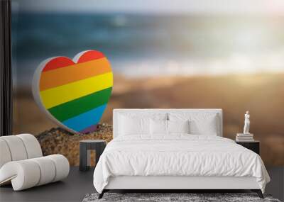 Heart of the color of the gay flag on the sand with the sea on background. LGBT concept. Gender equality concept. Copy Space. Romantic trip gay honeymoon. Same-sex couple.  Wall mural