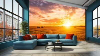 Sunset on the field with haystacks in Autumn season. Rural landscape with cloudy sky background in a sunny evening. Wall mural