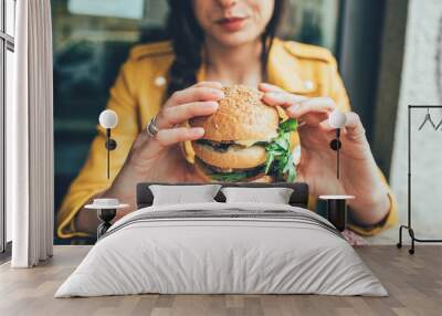 Close up on the hands of a young woman sitting holding an hamburger - hunger, food, meal concept Wall mural