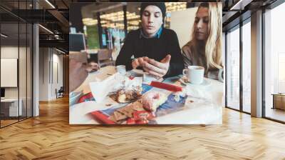 Two beautiful friends sitting bar indoor using smart phone Wall mural