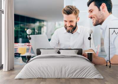 two young bearded caucasian modern business man sitting in a bar, using laptop, looking downward, ta Wall mural