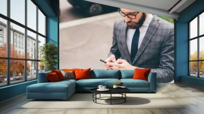 Young bearded elegant businessman outdoors using smartphone Wall mural