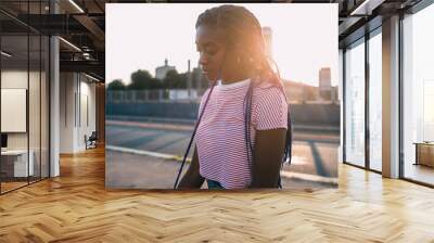 Young beautiful black woman standing alone outdoor backlight pensive Wall mural