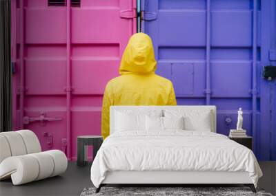 back view of woman with hood wearing yellow raincoat over pink and purple background. Colorful lifestyle Outdoors Wall mural