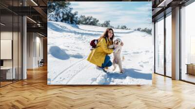 backpacker woman hiking outdoors with cute poodle dog. Snowy mountain in winter season. nature, pets and lifestyle Wall mural