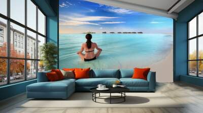 Young woman exercising yoga in turquoise lagoon with overwater b Wall mural