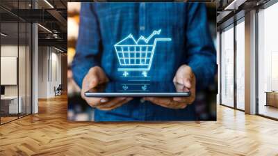 The growth of online shopping concept with a man holding tablet and shopping cart increase line chart graph Wall mural