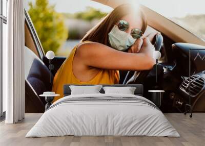 relaxed young woman in a car wearing protective mask. Summer season. prevention corona virus concept Wall mural