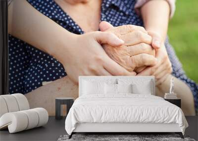 Close-up of the hands of a young woman hugging the hands of an old lady. Wall mural