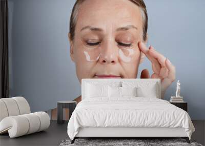 Mature woman applying patches under her eyes. Face skincare in older age Wall mural