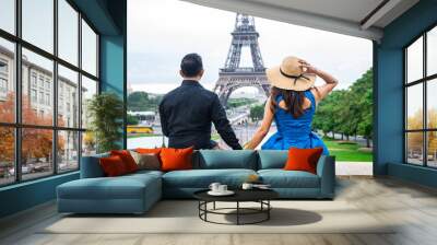 Young couple of tourists sitting in front of Eiffel tower in Paris Wall mural