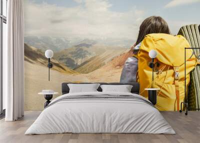 Close up view from the back unrecognizable woman with yellow stylish backpack with flask sticking out of the side pocket. Mock up copy space banner. Woman watch mountains valley in sunny day Wall mural