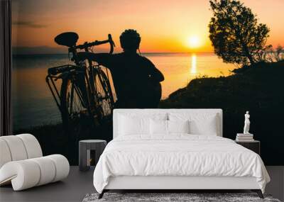 Silhouette cyclist traveler by his bicycle enjoy sunset view together by tranquil Sevan lake nature. Bicycle touring outdoors in nature. Self care and recreational sports activities. Weekend get away  Wall mural