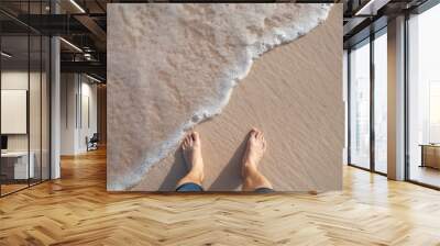 Barefoot male legs stand on wet coastal sand Wall mural