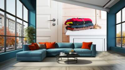 Colorful fleece jackets laying on a white chest of drawers Wall mural