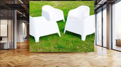 Four modern white plastic chairs stand on green grass Wall mural