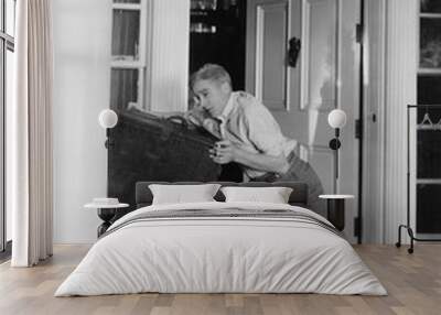 Man moving heavy trunk  Wall mural