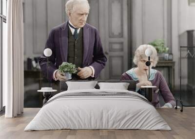 older man standing next to a woman at her desk Wall mural