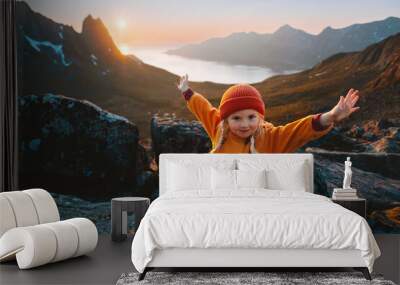 Child girl hiking in mountains travel vacations in Norway adventure outdoor active healthy lifestyle 4 years old kid happy raised hands enjoying midnight sun landscape Wall mural