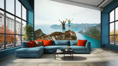 Couple friends traveling together on cliff edge in Norway man and woman family healthy lifestyle concept summer vacations outdoor success happy emotions raised hands holding Wall mural