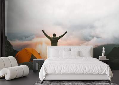 Man traveler happy raised hands on mountain top near of tent camping outdoor Travel adventure lifestyle success concept hiking active vacations enjoying sunset view Wall mural