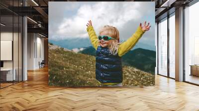 Toddler happy raised hands hiking in mountains family travel vacations healthy lifestyle 2 years old child outdoor having fun Wall mural