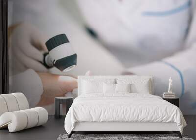 Closeup of dermatologist examining mole on hand of female patient in clinic Wall mural