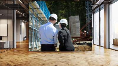 Two architects a man and a woman in construction in white helmets. Wall mural