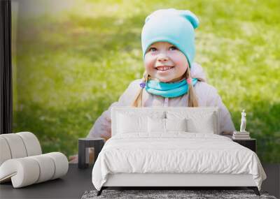 Autumn portrait of a little girl in a hat and jacket. Little girl laughing and smiling in the park on the grass. Happy girl Wall mural