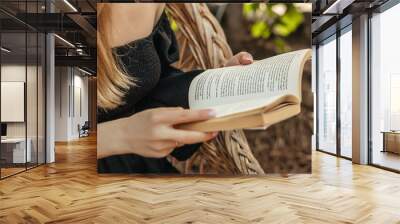 female hands holding a vintage book. girl reading a book sitting on a straw chair Wall mural