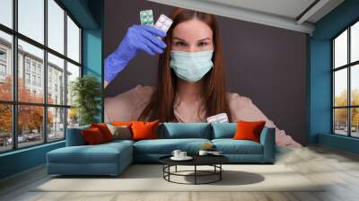 Portrait of woman in protective mask holding pills Wall mural