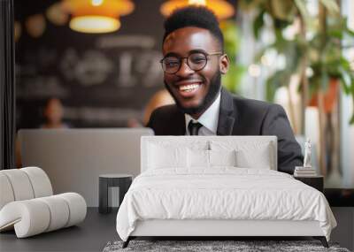 Smiling African American freelancer in a black suit working on laptop at a vibrant cafe Wall mural