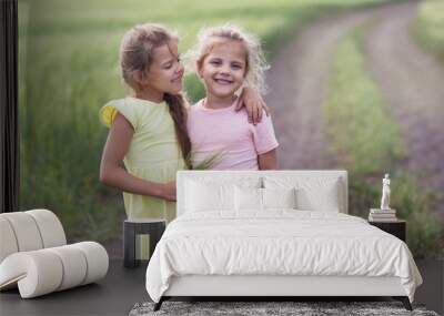 Two little girls hug and smile in nature Wall mural