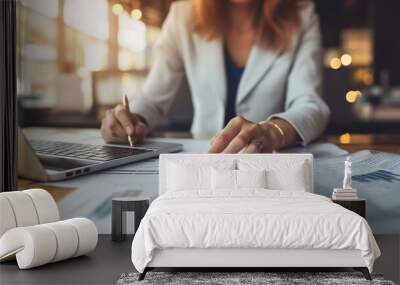 Woman analyzing financial charts on papers with laptop, report concept Wall mural