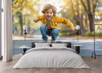 A young boy is riding a skateboard down a street. He is smiling and he is enjoying himself Wall mural