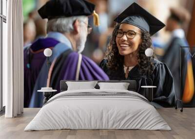 Confident young female college graduate in cap and gown at graduation ceremony shaking hands with unrecognizable professor. Wall mural