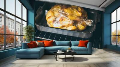 Chicken legs and sliced potatoes in roasting bag on baking tray in oven. Wall mural