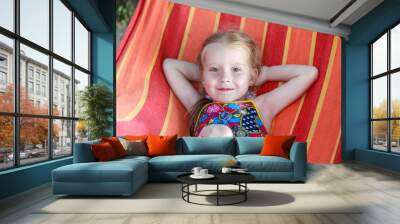 Concept summer, vacation, weekend- beautiful blond-haired girl with blue eyes is lying on a bright hammock with rainbow colors Wall mural